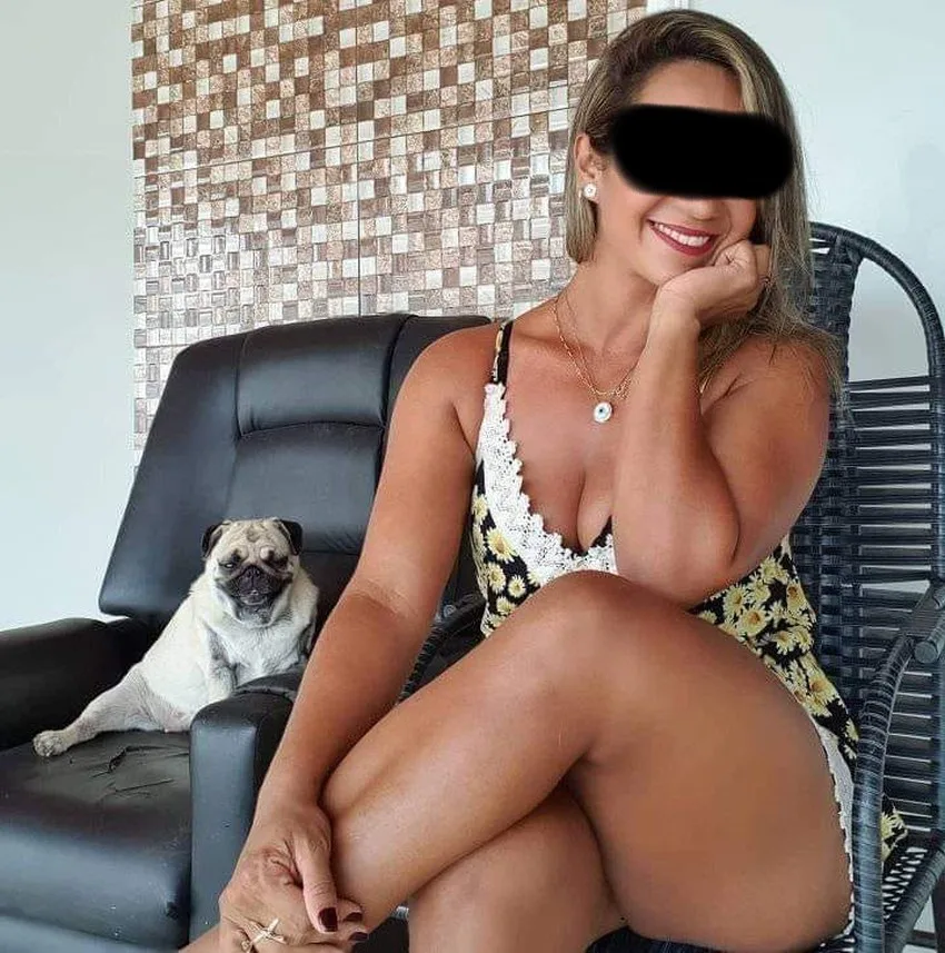 Belle femme mûre et pulpeuse assise sur une chaise avec un chien à côté d'elle